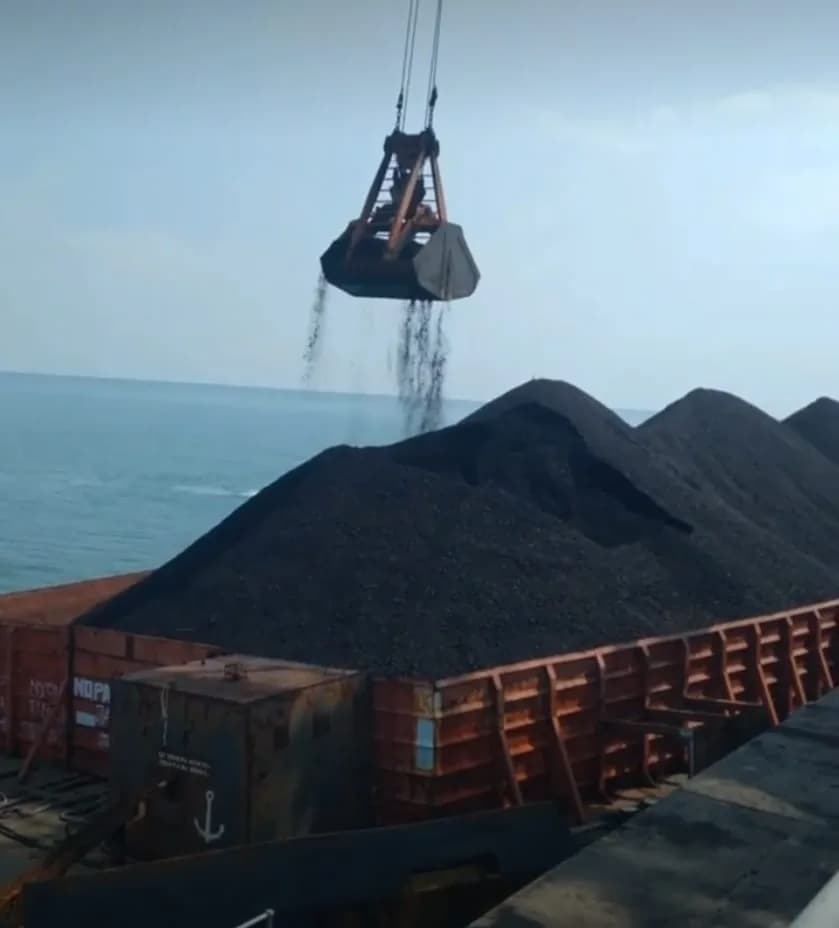 Grab crane loading bulk material into a barge