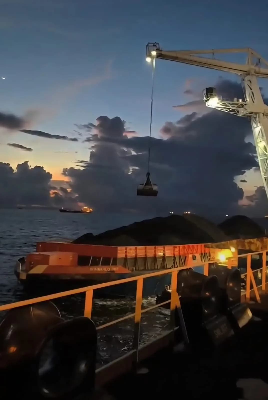 Crane and loaded barge at dusk